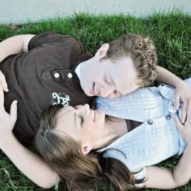 Couple laying on grass with heads on each other's shoulders