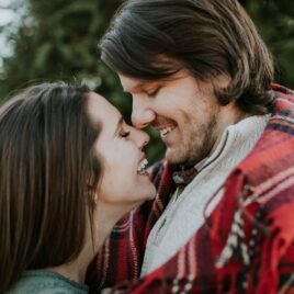 Couple snuggling up together in the cold in a plaid blanket | The Dating Divas