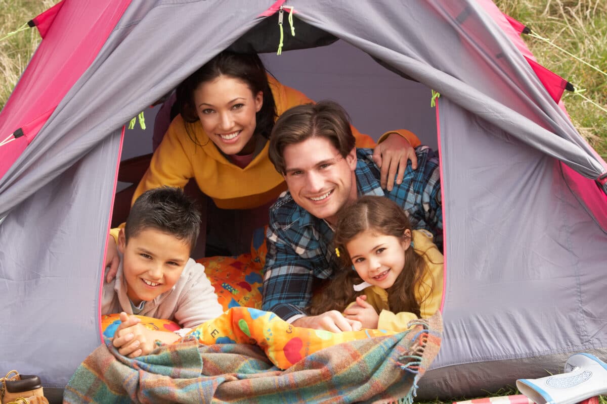 Two parents and their kids camping in a tent | The Dating Divas
