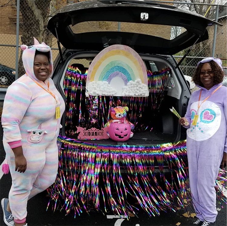 Trunk decorated with a care bear theme including a large rainbow and coordinating Care Bear costumes. This is a great trunk or treat idea | The Dating Divas