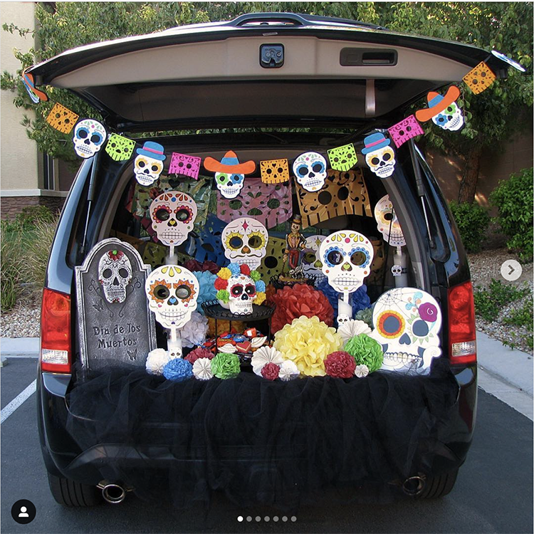 Trunk decorated with a day of the dead (dia de los muertos) theme. It is a colorful display with skeletons, flowers and papel picado. A fun trunk or treat idea. | The Dating Divas