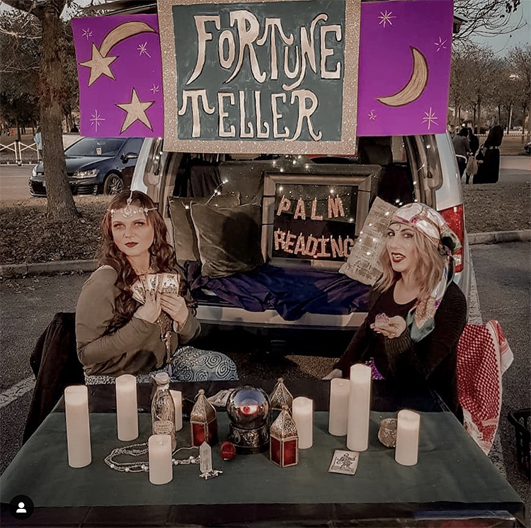 A trunk decorated with candles, moons and stars. There are two women dressed as fortune tellers. There is a table. The idea for this trunk is to not only get a candy but also to get your fortune told. A fun interactive trunk or treat idea. | The Dating Divas