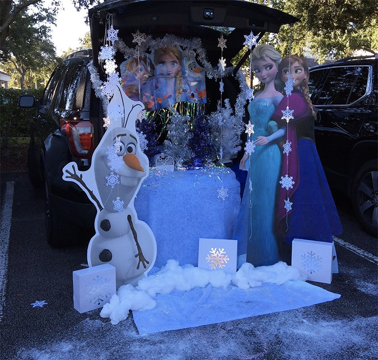 Trunk decorated with a theme for Disney's frozen. It includes snowflakes and stand up cardboard cut outs of characters from the show. This is a great trunk or treat idea | The Dating Divas