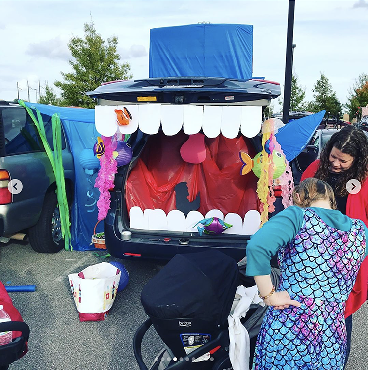 A trunk decorated as a large whale. Inside of the whale is the silhouette of a man praying (Jonah). This is a great trunk or treat theme for church! | The Dating Divas