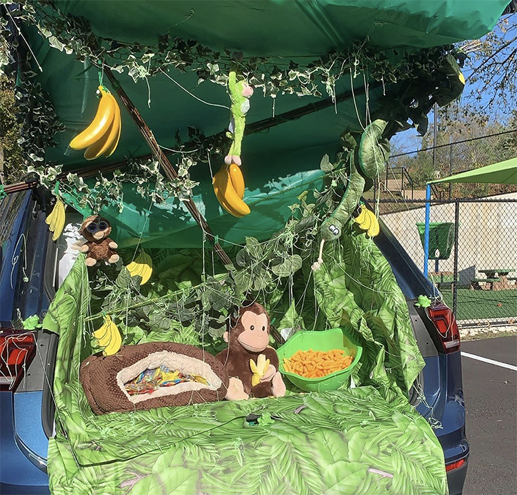 A trunk decorated as a jungle. It includes a lot of greenery, banana and a stuffed monkey. This is a fun trunk or treat theme idea for family animal costumes to do with the theme. |The Dating Divas