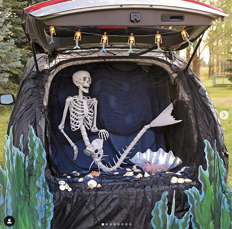 A trunk decorated with an under the sea scene. Inside the trunk is a skeleton mermaid. This is a fun idea for a scary trunk or treat theme | The Dating Divas