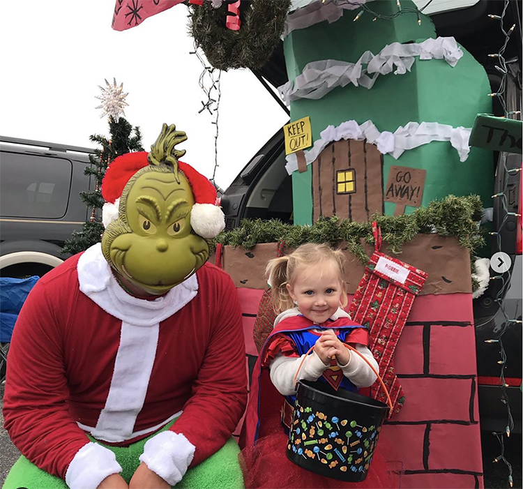 Trunk decorated with a theme for the movie and book The Grinch Who Stole Christmas. It includes scenes from Whoville. A parent and child is seen in a Grinch and Cindy Lou costume to coordinate with the trunk's theme. This is a great trunk or treat idea | The Dating Divas