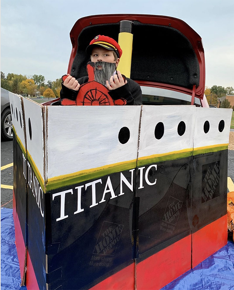 A trunk decorated like the ship, Titanic. A blue tarp creates the image of an ocean and a costumed boat captain is at the hull of the ship. This is a unique Trunk or Treat idea that people will recognize and love! | The Dating Divas