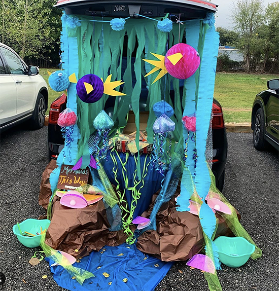 A trunk decorated with an under the sea theme. It includes colorful fish and blue streamers. This is a very colorful trunk or treat decorating idea! | The Dating Divas