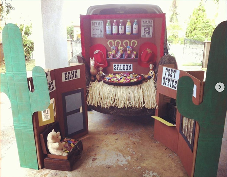 Trunk decorated as a Wild West scene. It includes various buildings including a post office, bank and saloon. There are cacti and wanted posters. This is a great trunk or treat idea for Halloween | The Dating Divas