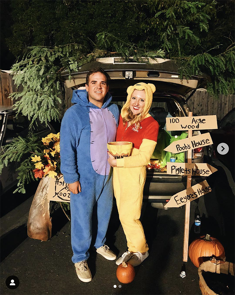 Trunk decorated with a theme for the movie and book Winnie the Pooh. It includes signs for the 100 acre woods. A couple is dressed as Eeyore and Winnie the Pooh to coordinate their costumes with the trunk's theme. This is a great trunk or treat idea | The Dating Divas