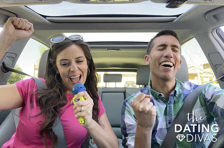 Couple in a car singing along to fun road trip songs. | The Dating Divas