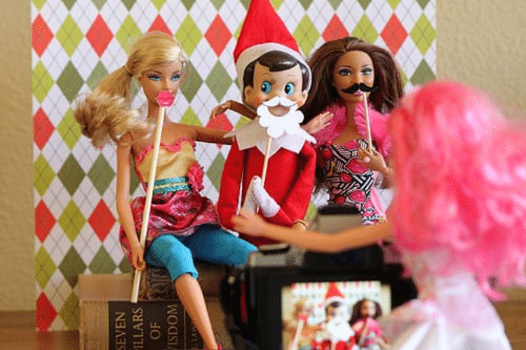 Elf on the shelf using photo booth props with friends | The Dating Divas