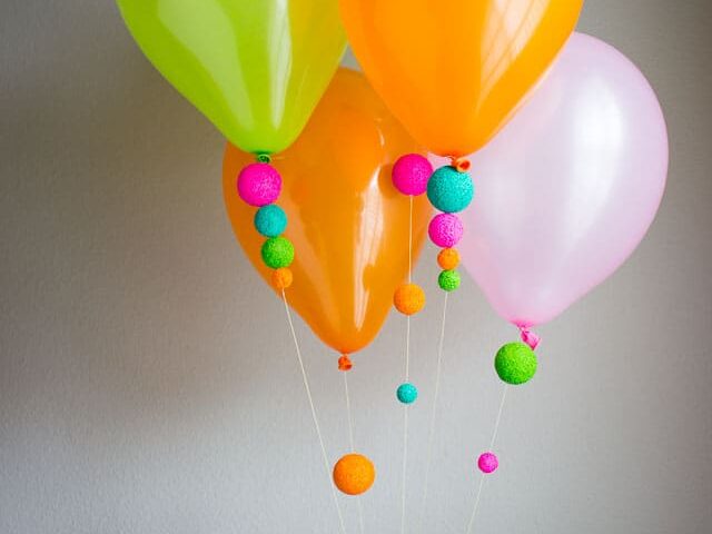 Neon-painted Styrofoam balls are added to the strings of balloons for a birthday party decoration | The Dating Divas