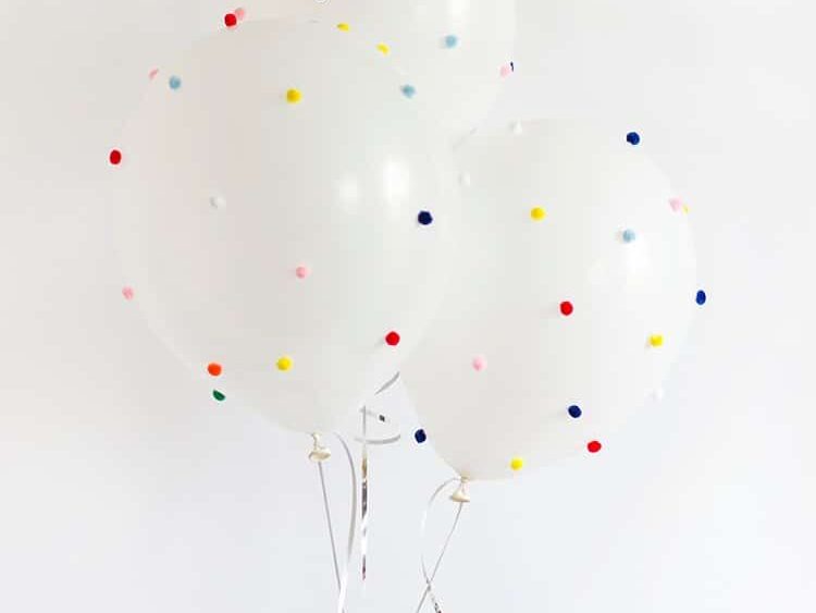 Add colorful pom-poms to balloons for birthday decoration ideas | The Dating Divas