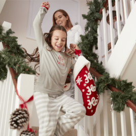 Little girl holding stocking running down the stairs on Christmas morning | The Dating Divas