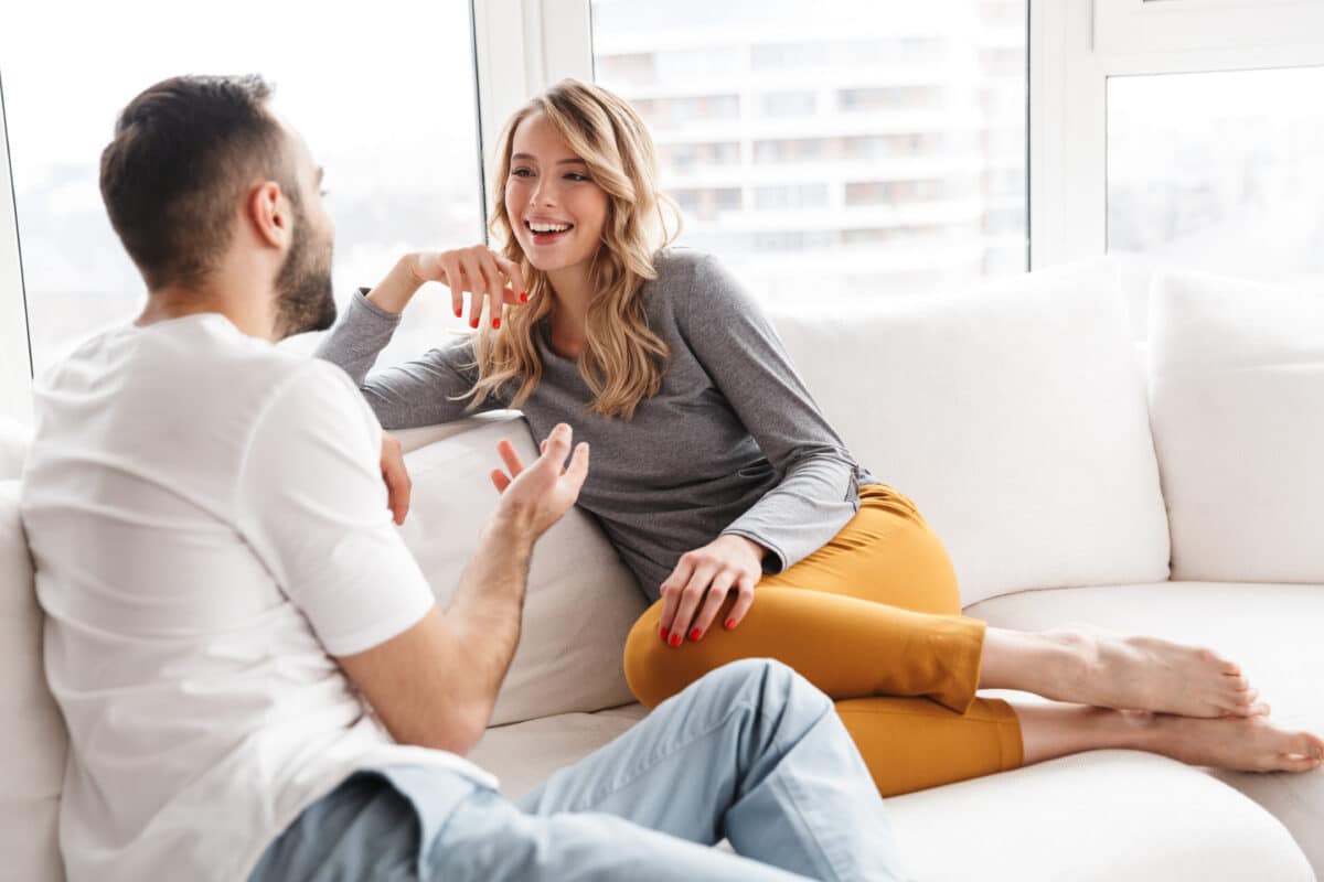 A man and woman working on effective communication while sitting on the couch | The Dating Divas