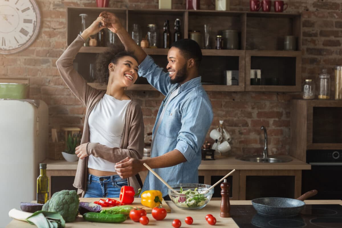 Couple enjoying a cooking dinner date using one of our best cookbooks. | The Dating Divas