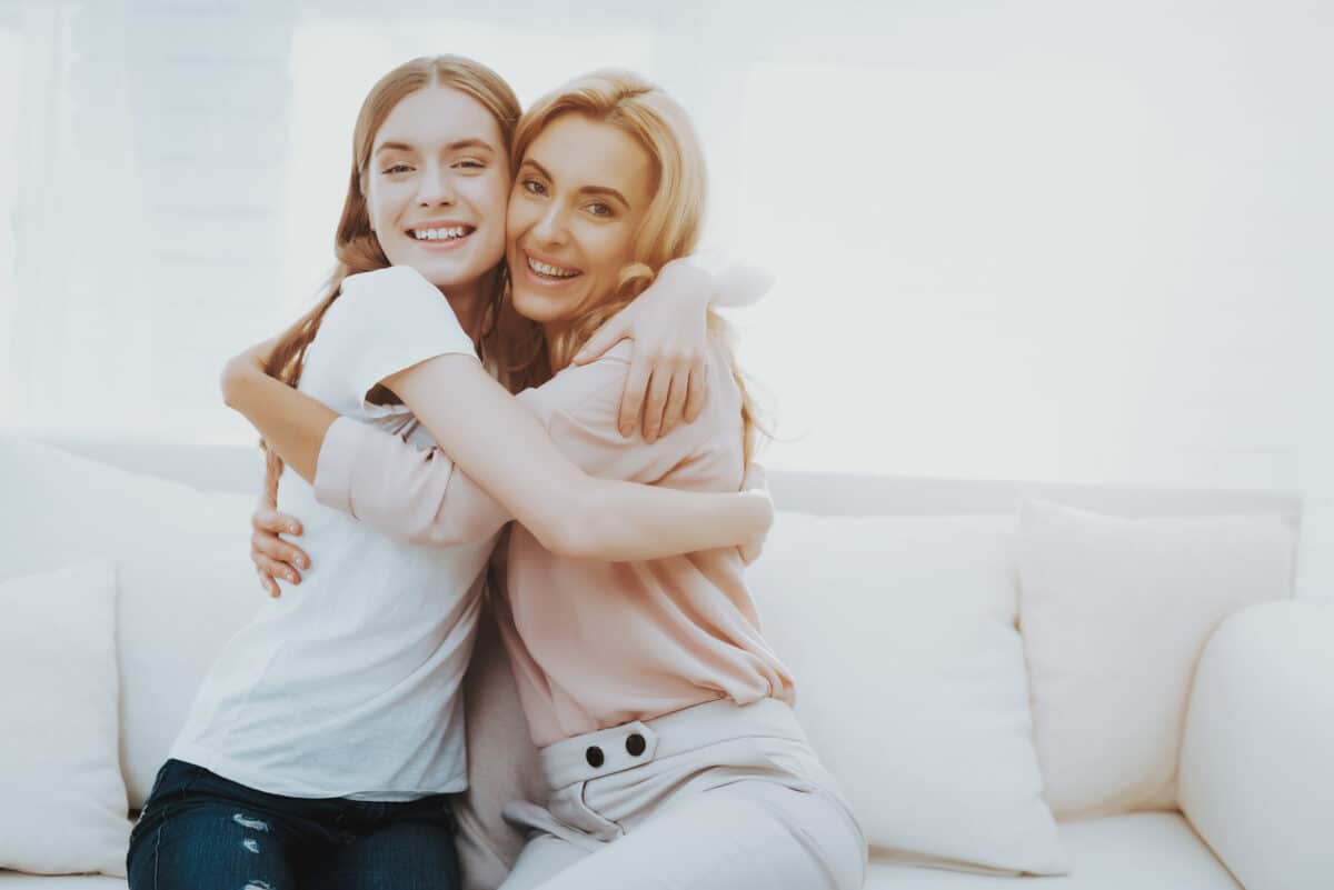 Mother is an example of good parenting as she smiles and hugs her teenager | The Dating Divas