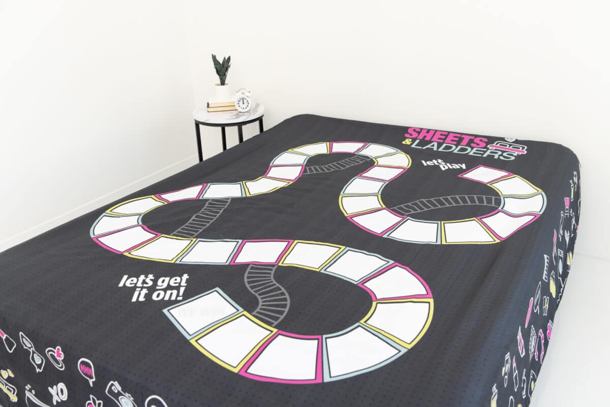 The Sheets & Ladders bedsheet board game laid out on the bed | The Dating Divas