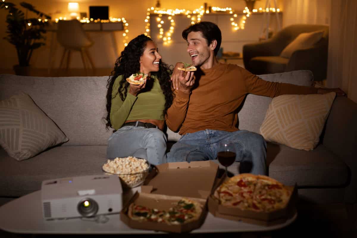 A couple enjoying cute date ideas for their next movie night at home together | The Dating Divas