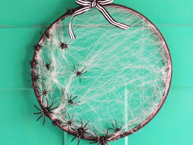 Make DIY Halloween decorations using an embroidery hoop, fake spiders, and fake spiderwebs.  | The Dating Divas