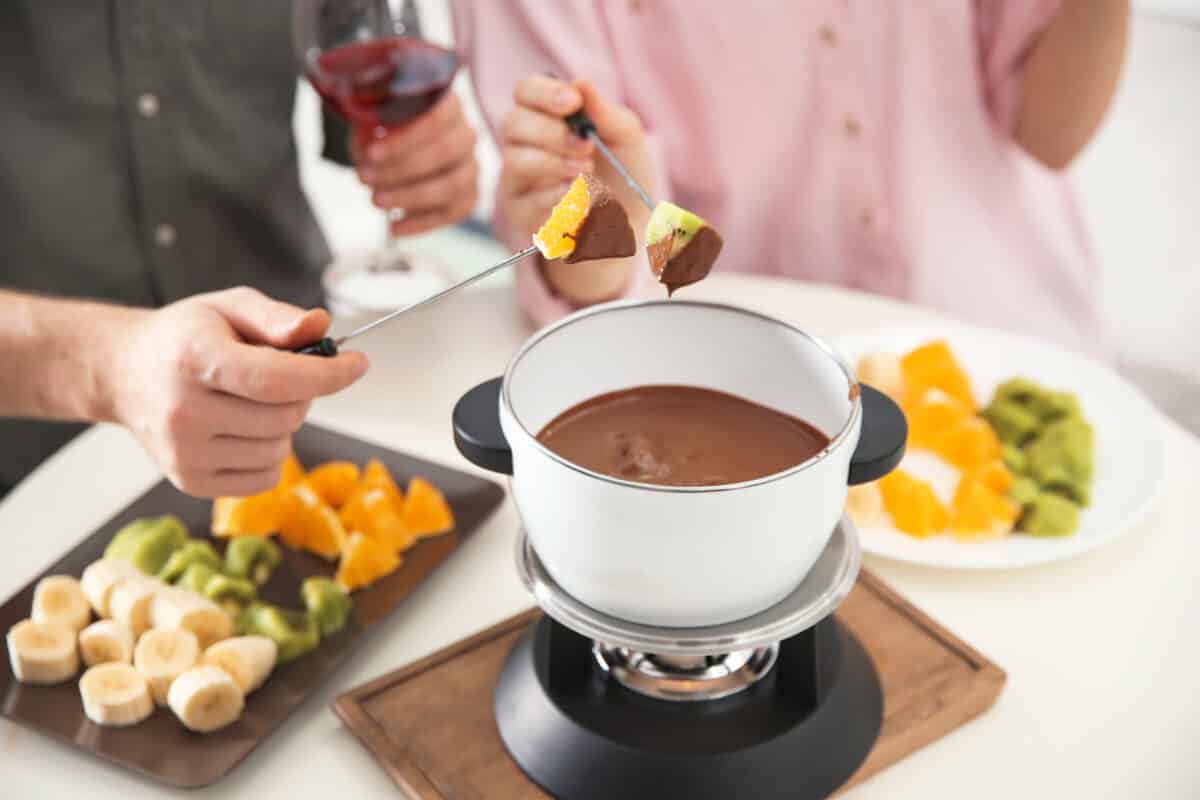 A man and woman making fondue together while trying out fun date ideas for foodies | The Dating Divas