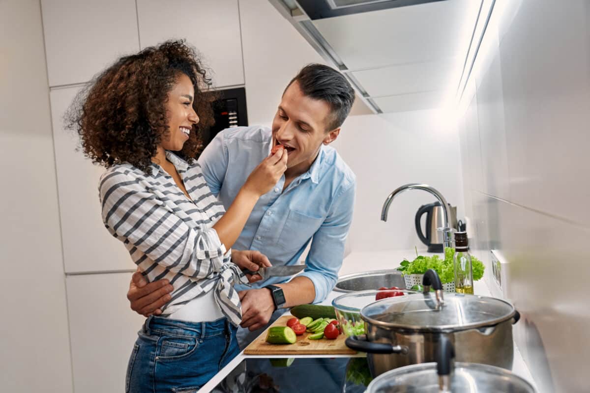 A man and woman experiencing fun date ideas while cooking and eating together | The Dating Divas