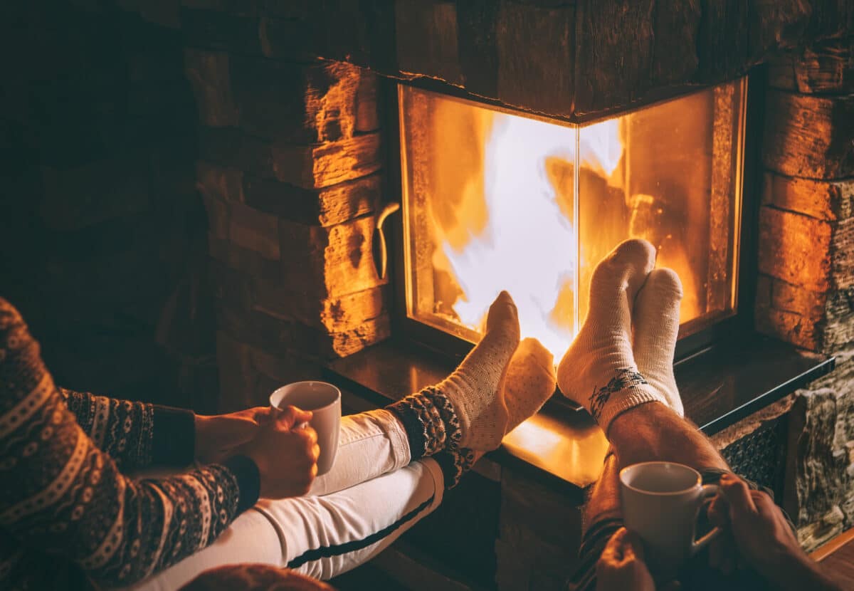 Husband and wife sitting fireside and drinking hot cocoa together to combat feelings of homesickness | The Dating Divas