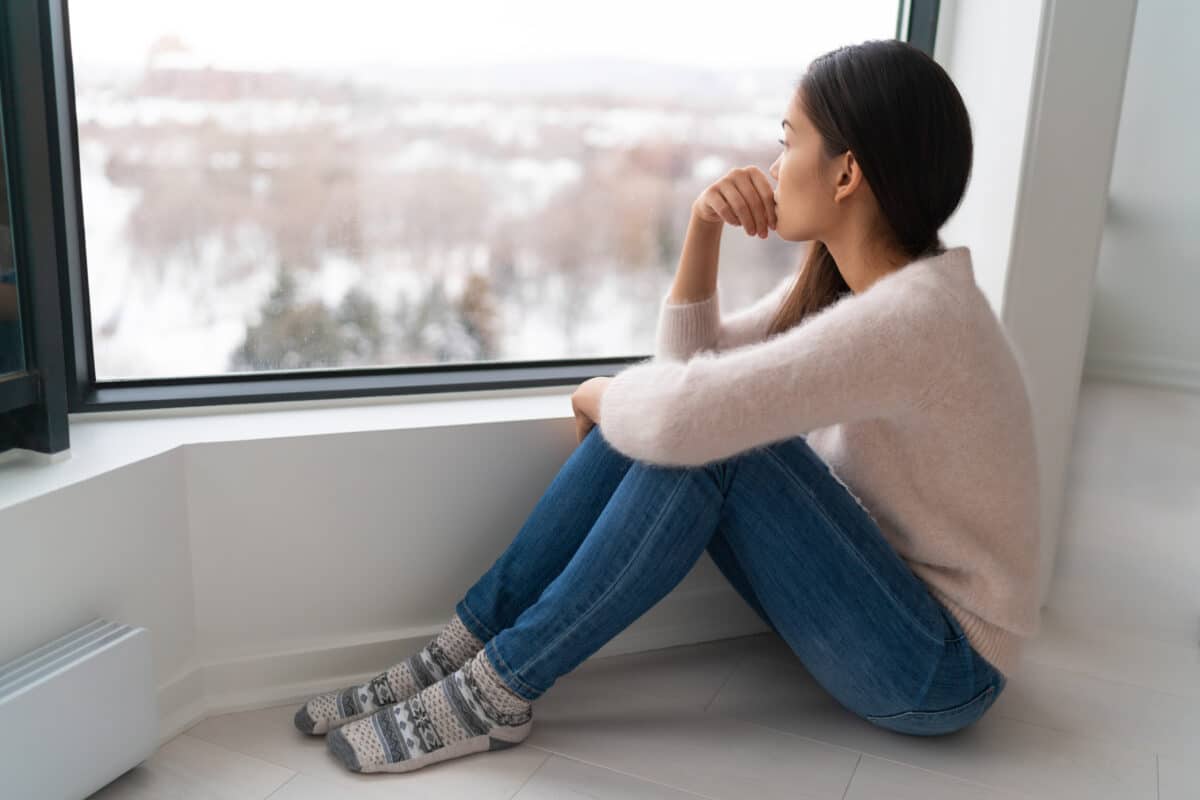 Lonely woman sits at a window wondering how she can find a support system | The Dating Divas