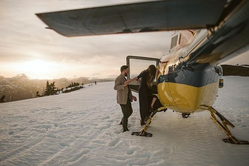 A winter image that shows a man and woman boarding a helicopter in the snow | The Dating Divas