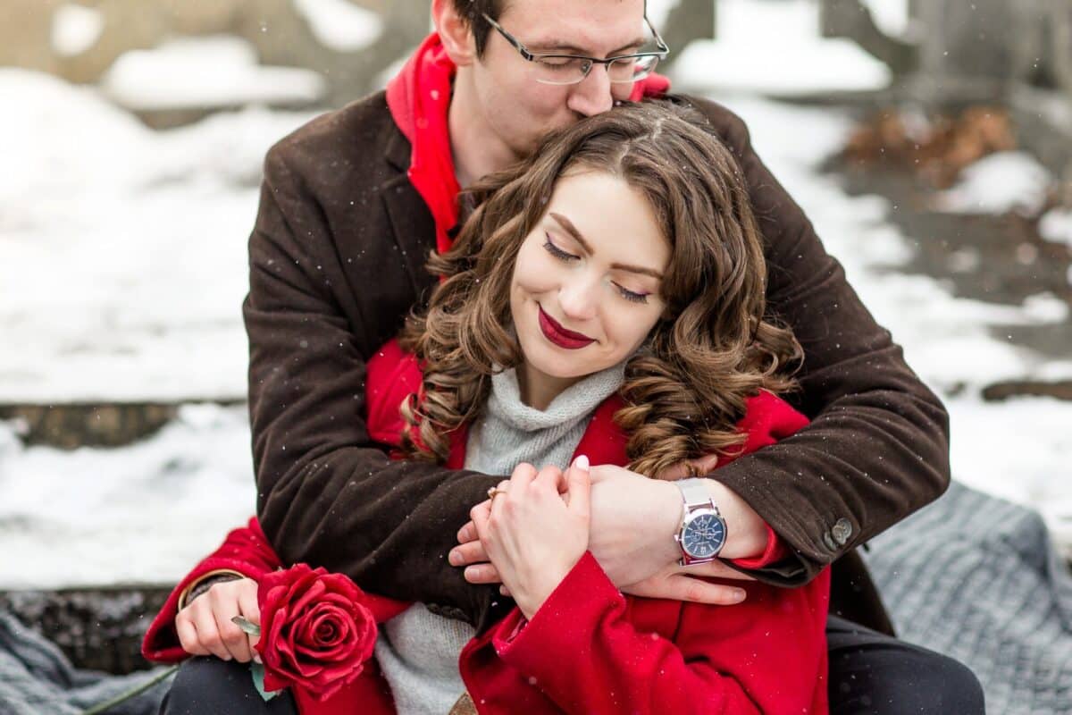 A man and woman embracing during their winter engagement photos | The Dating Divas