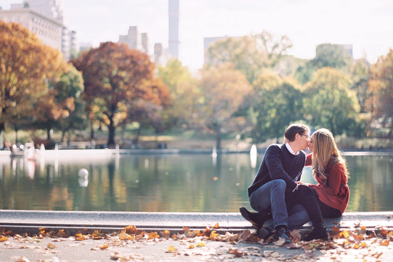 Winter engagement photo ideas showing a couple kissing near a fountain | The Dating Divas