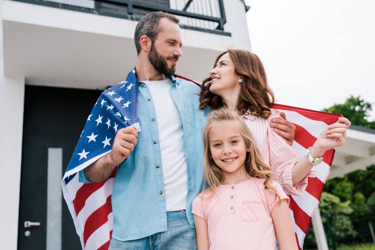 A family enjoys 4th of July quotes about their freedom as they stand and honor the U.S. flag. | The Dating Divas
